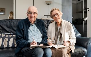 Man en vrouw op de bank met allebei een puzzelboekje in de hand.