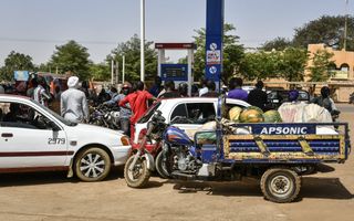 Auto’s, motoren en mensen bij een benzinestation.