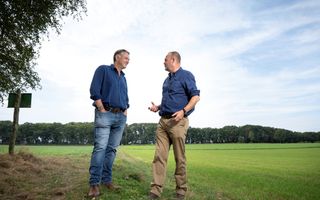 Twee mannen aan de rand van een grasvlakte.