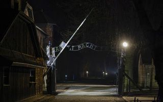 Entreehek met de beruchte woorden Arbeit macht frei. De foto is gemaakt in het donker.