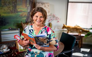 Glimlachende vrouw in een woonkamer met een boek over vossen in haar hand