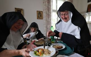 Drie oude vrouwen bij hun bord met eten.