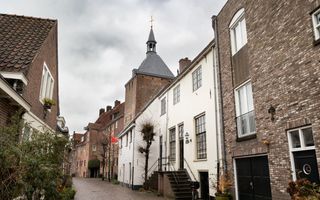 Groot wit gebouw te midden van oude en nieuwe stadspanden.