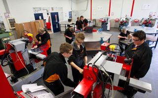 Jongeren zijn samen bezig met machines in een klaslokaal. 