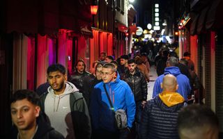 Mannen lopen door een straat in het Amsterdamse prostitutiegebied de Wallen. 