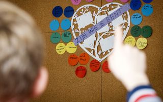 Een jongetje steekt zijn vinger op. Achter hem hangt een groot hart met de tekst ”Zijn wie je bent”, en daaromheen woorden die hierbij zouden passen, zoals ”respect”.