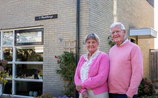 Een ouder echtpaar staat voor een huis met de naam ’t Wachthuisje. 