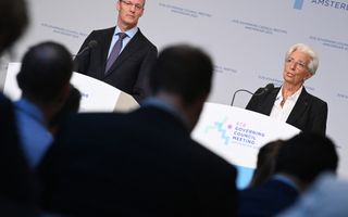 Een man met stropdas en een vrouw met kort, grijs haar staan beiden achter een eigen katheder met eigen microfoon. De vrouw praat. 