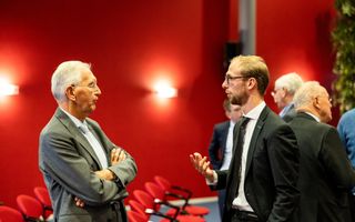 Twee mannen, in pak, met elkaar in gesprek.