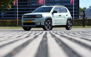Een mintgroene auto staat voor een flatgebouw. In het deurpaneel staat het woord Panda. De auto oogt modern met onder andere koplampen die uit meerdere lichtblokjes bestaan.