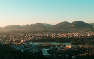 foto van een stad in een dal bij avondlicht; op de achtergrond een reeks bergen
