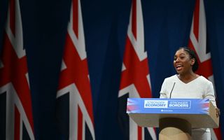 Een vrouw in een witte jurk staat voor Britse vlaggen. 