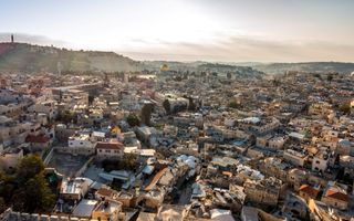 Zicht op Jeruzalem, met vele huizen en een goudkleurige koepel.