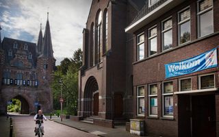 Stenen kerkgebouw van de zijkant gefotografeerd met blauw reclame-spandoek voor de Alphacursus.