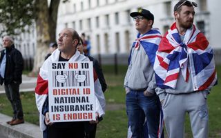 Twee mensen met een Engelse vlag om zich heen, een persoon houdt een tekstbord vast met daarop „Say no to digital ID”.
