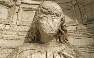 Oud religieus stenen beeld in een nis met beschadigd gezicht.