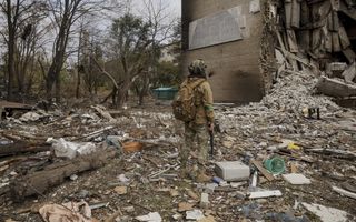 Een Oekraïense soldaat loopt voor een beschadigd gebouw.