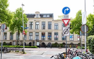 Statig gebouw aan doorgaande weg, met op de voorgrond veel fietsen.