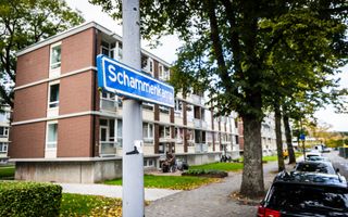 Flat met drie verdiepingen. Ervoor een straatnaambordje met de tekst ”Schammenkamp”. Rechts geparkeerde auto’s, in het midden enkele bomen. 