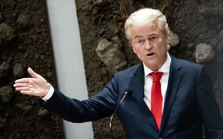 PVV-voorman Geert Wilders, een man met wit achterover gekamd haar. Hij draagt een blauw pak met een rode stropdas. 