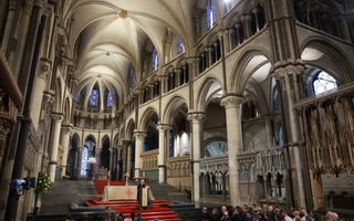 In de kathedraal van Canterbury staat een vrouwelijke bisschop achter een katheder terwijl ze een groep kerkgangers toespreekt.