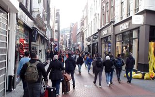Mensen lopen door een drukke winkelstraat.