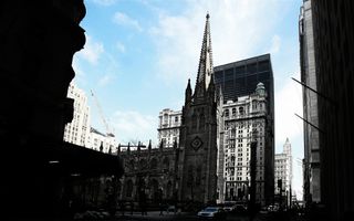 Foto van een klassiek kerkgebouw in een omgeving met veel hoogbouw.