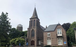 Rooms-katholiek kerkgebouw naast een woning. Op de achtergrond een watertoren.