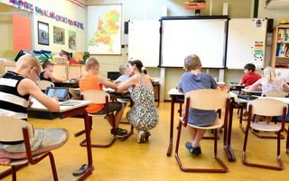 Een juffrouw helpt een leerling, in een klaslokaal.