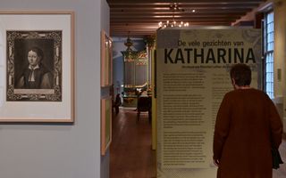 Een vrouw staat bij een informatiepaneel over ”De vele gezichten van Katharina”.