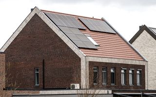 Zwarte zonnepanelen liggen op het dak van een woning met rode dakpannen.
