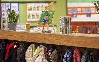 Een leesboekje staat in een houder op een kast in een school. 