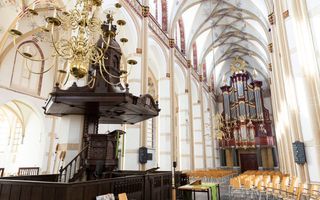 Oud kerkinterieur met stoelen, op de achtergrond het grote orgel.  