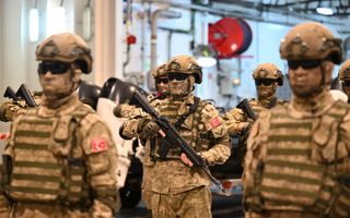 Soldaten in camouflagekleding met grote geweren poseren op een schip.