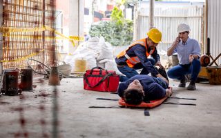 Veiligheidsteam helpt een bouwer na een ongeval op een bouwplaats - concepten voor gezondheid en veiligheid op het werk