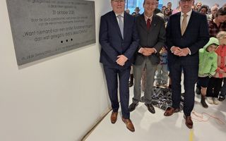 Drie mannen in pak, achter hen gezinnen met kinderen.