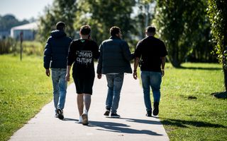 Vier mannen met buitenlands uiterlijk lopen op een weggetje.