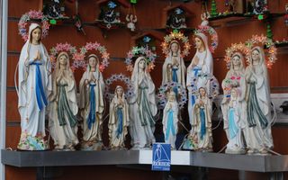Stenen beeldjes van Maria, gekleed in wit en blauw.