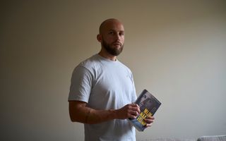 Man met baard met het boek ”Mijn naam is Edino” in de hand.