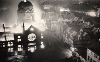 Vlammen slaan uit een grote synagoge met een koepel in een nacht.