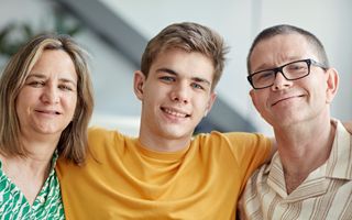 Een jongen staat tussen zijn beide ouders in