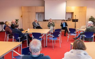 Een groep mensen rondom tafels met elkaar in gesprek.