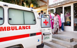 Hoogzwangere vrouw wordt door verpleegkundige naar de ambulance begeleid.