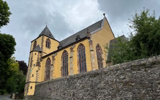 Oud kerkgebouw met een gele buitenmuur, hoge ramen.