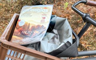 In een fietsmand ligt een exemplaar van de GezinsGids, waarvan de voorkant dezelfde kleuren heeft als de bladeren buiten.
