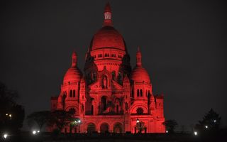 grote basiliek met ronde torens steekt roodverlicht af tegen een nachtelijke hemel.