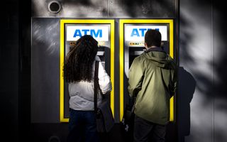Mensen pinnen geld bij een pinautomaat in het centrum van Amsterdam