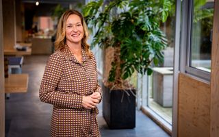 Vrouw in ruitjesjurk met kantoor als achtergrond.