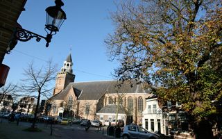 Oude kerk, met links een torentje. Op de voorgrond een grote parkeerplaats.