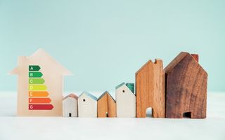 Houten huis met energielabel, daarnaast nog enkele houten speelgoedhuisjes. 